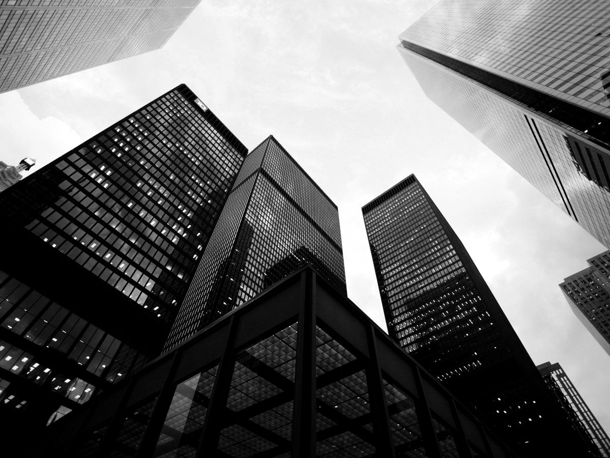 Looking up at dark glass office towers against a pale sky
