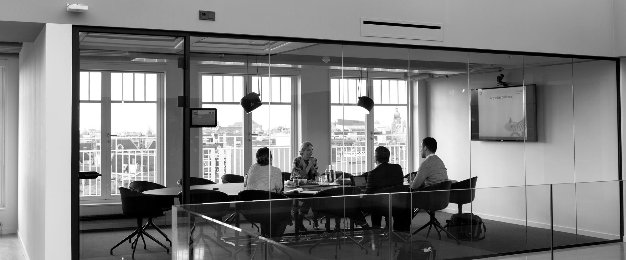 A team meeting around a table in a glass-walled conference room